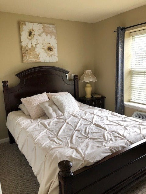 A cozy bedroom with a neatly made bed, side tables with lamps, and a floral painting on the wall.