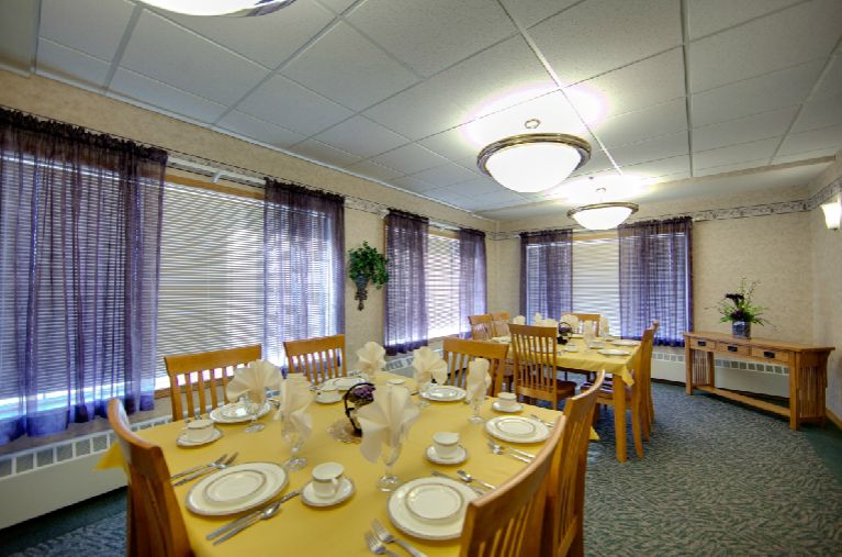 A well-set dining room with elegant tableware and warm lighting.