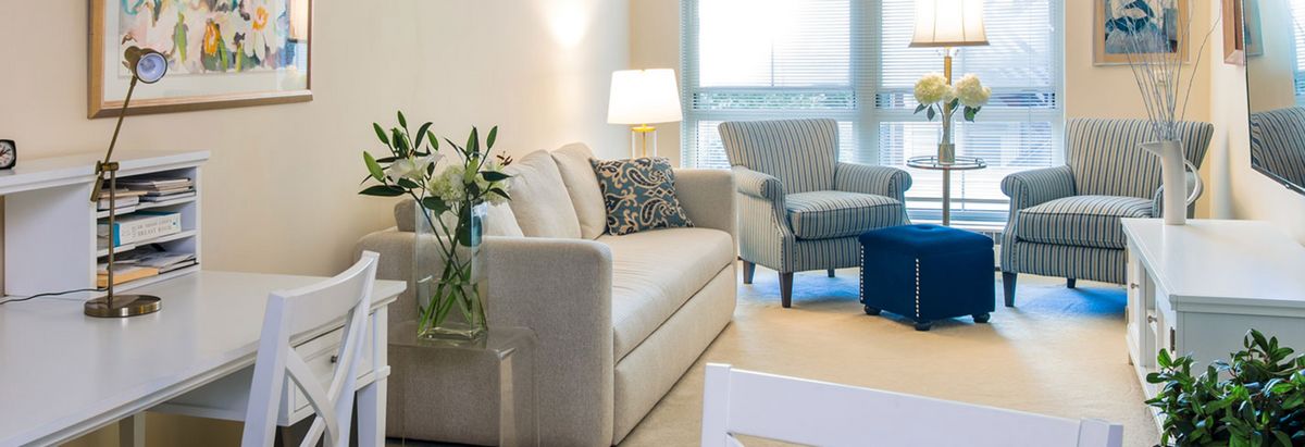 A cozy living room with a sofa, armchair, and table lamp creating a warm atmosphere.
