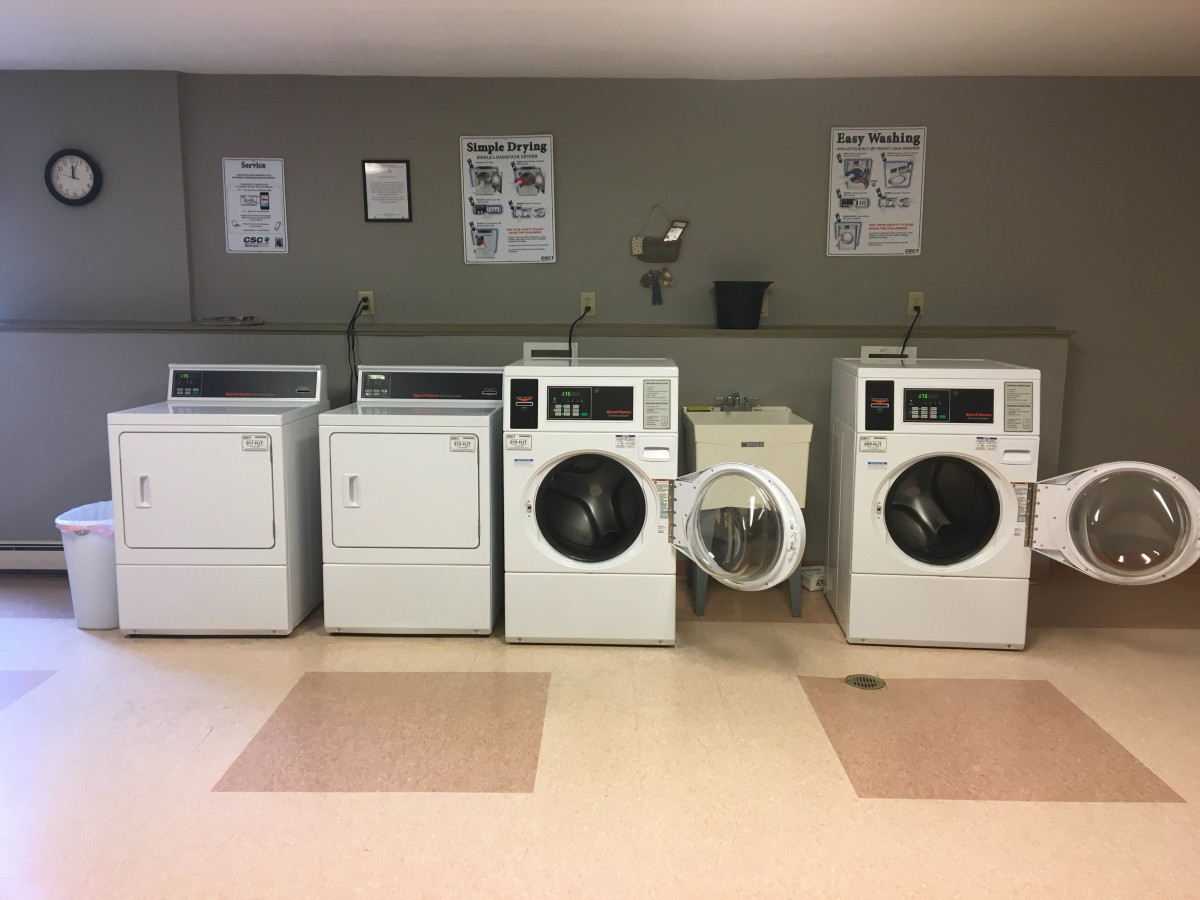 A laundromat with a row of washing machines and dryers.
