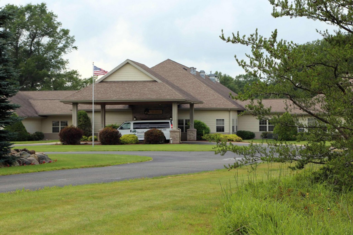 A suburban building with a driveway and surrounding greenery.