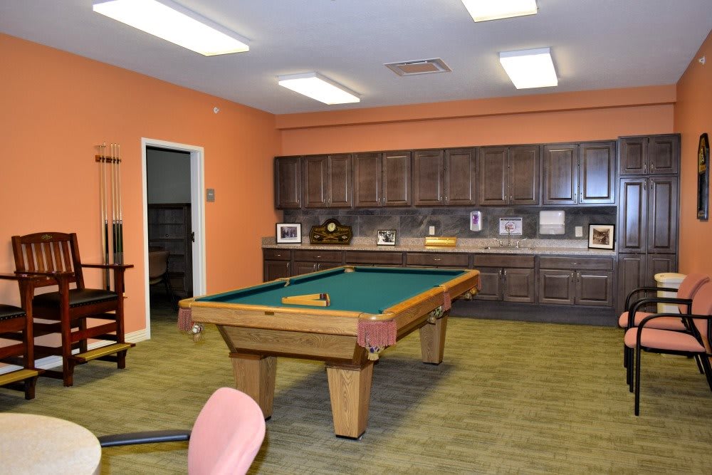 A game room featuring a pool table and a kitchen area with orange walls.