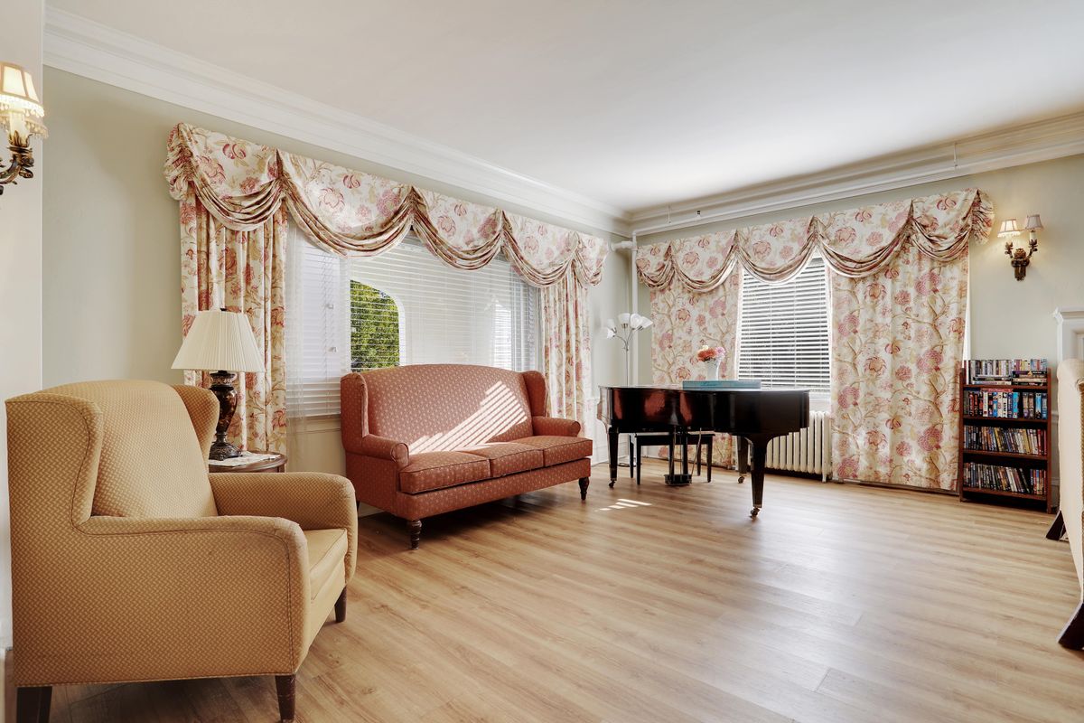 A traditional living room featuring a grand piano, a couch, an armchair, and elegant curtains.