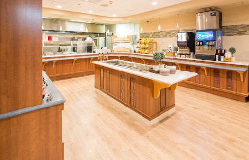 A spacious and modern kitchen buffet setup, featuring wooden cabinetry and various food stations.