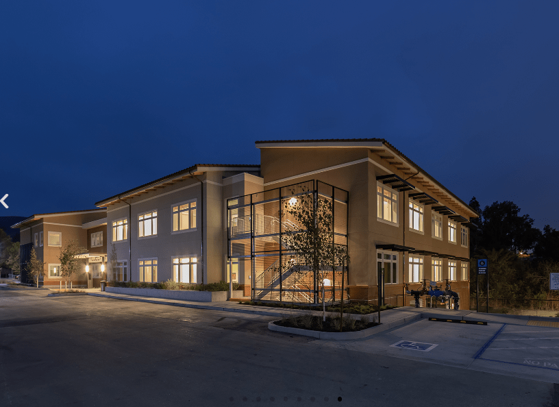 A modern two-story building illuminated at night, showcasing its architectural design with bright windows.