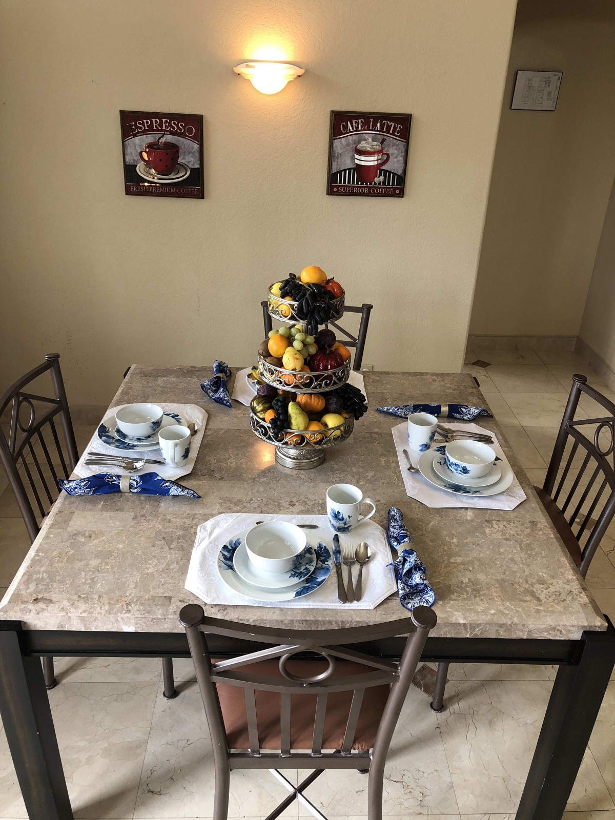 A neatly set dining table with a fruit centerpiece, ready for a meal in a cozy kitchen setting.
