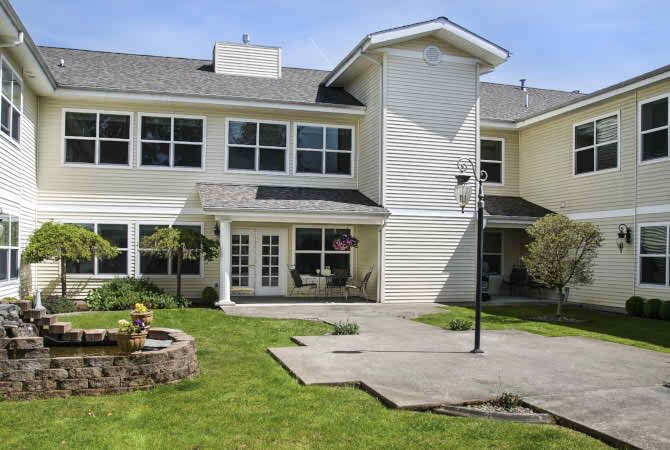 A two-story residential building with large windows and a well-maintained lawn.