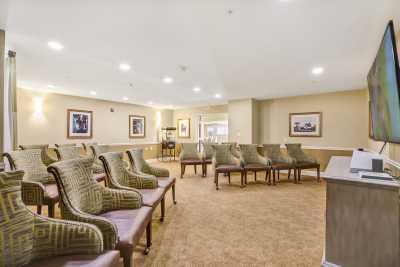 An empty conference room with rows of upholstered chairs and framed artwork on the walls.