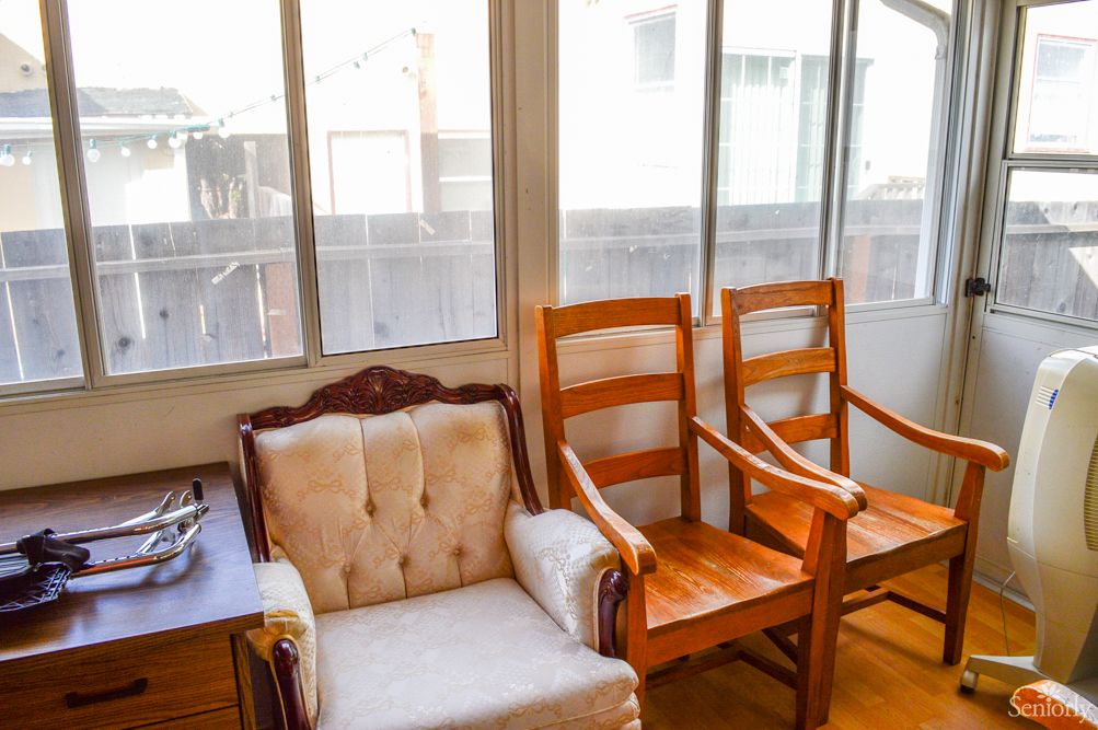 A cozy room with wooden chairs and a cushioned armchair by the window.