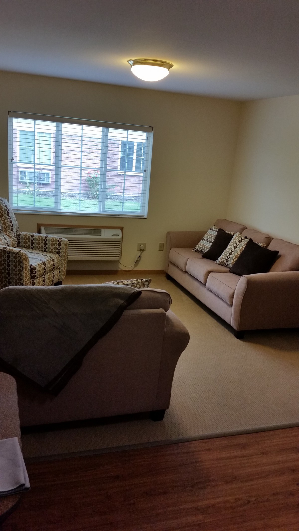 A cozy living room with two sofas and an armchair near a window.