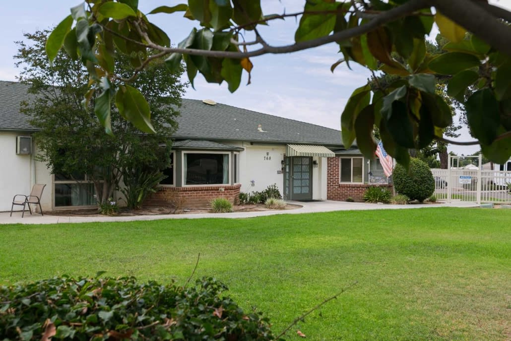 A suburban house with a well-maintained lawn and surrounding trees.