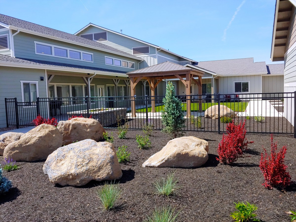 A landscaped garden with large rocks in front of a modern house.