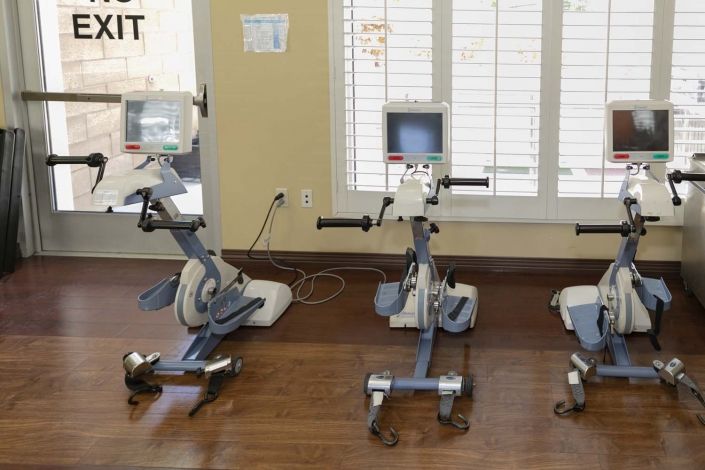Three exercise bikes lined up in a gym setting with wooden floors.