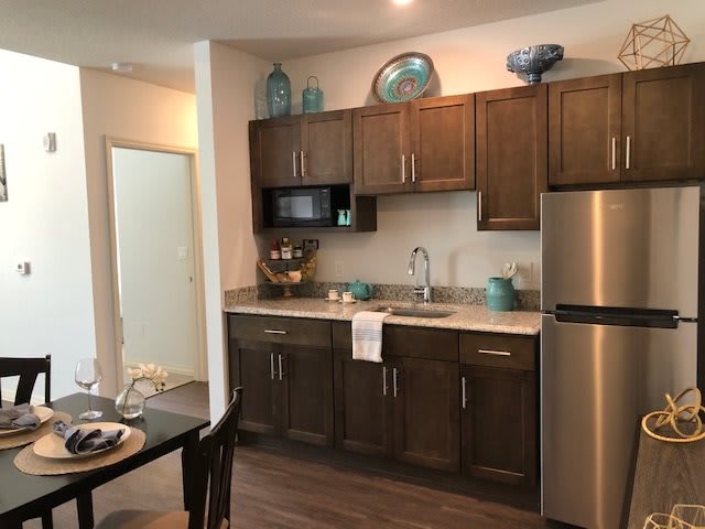 A modern kitchen with dark wooden cabinets, stainless steel appliances, and decorative items.