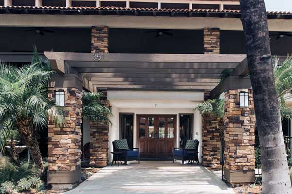 A welcoming building entrance with stone pillars and comfortable outdoor seating.