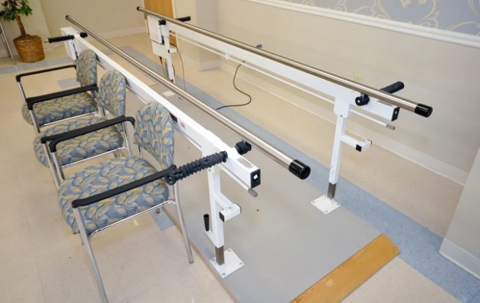 A set of parallel bars used for physical therapy and rehabilitation exercises in a therapy room.