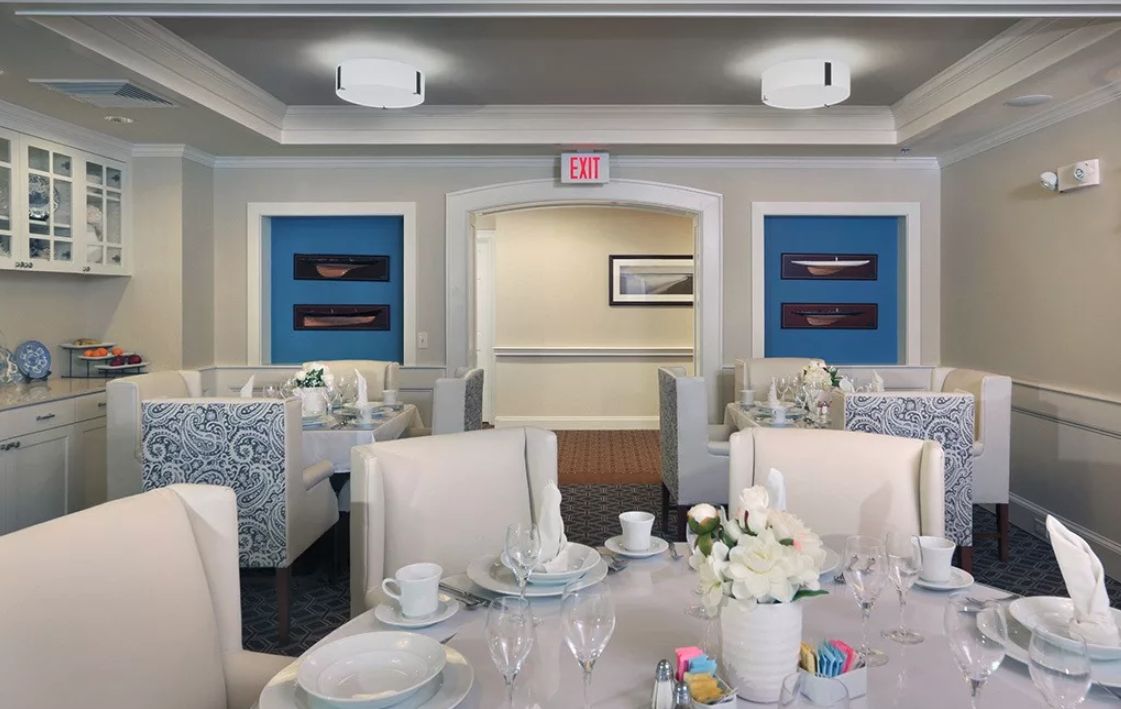 An elegantly decorated dining room with neatly set tables and upholstered chairs.