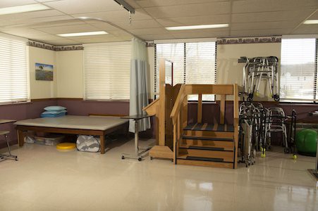 A physical therapy clinic with exercise equipment and a rehabilitation staircase.