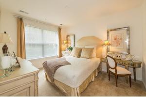 A cozy bedroom with neutral colors, featuring a comfortable bed, elegant decor, and ample natural light.