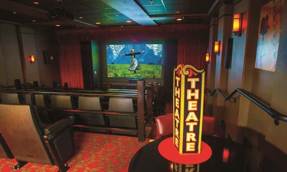 A cozy theater interior with rows of seating facing a screen displaying an animated scene.