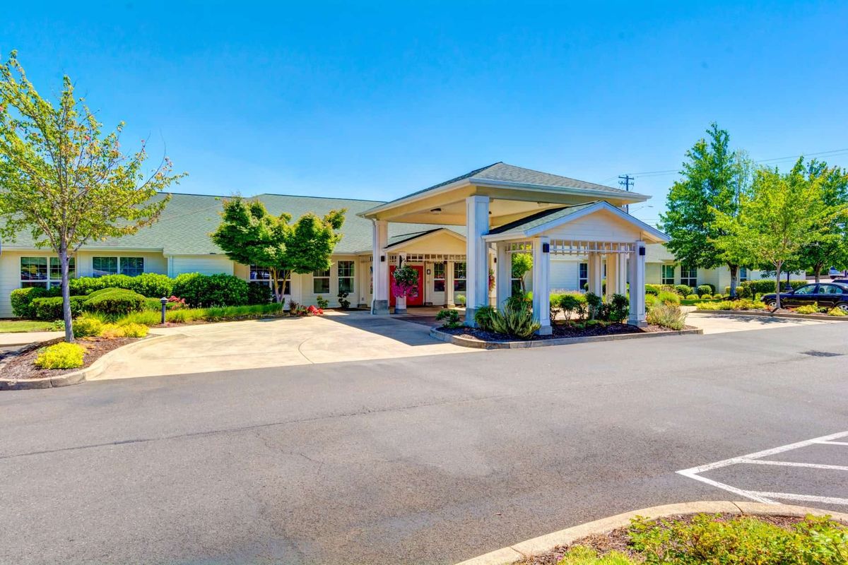 A sunny view of a building with a grand entrance and well-maintained landscaping.