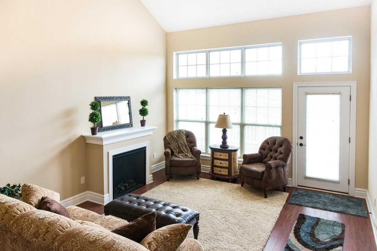 A cozy living room with a fireplace, large windows, and comfortable seating.