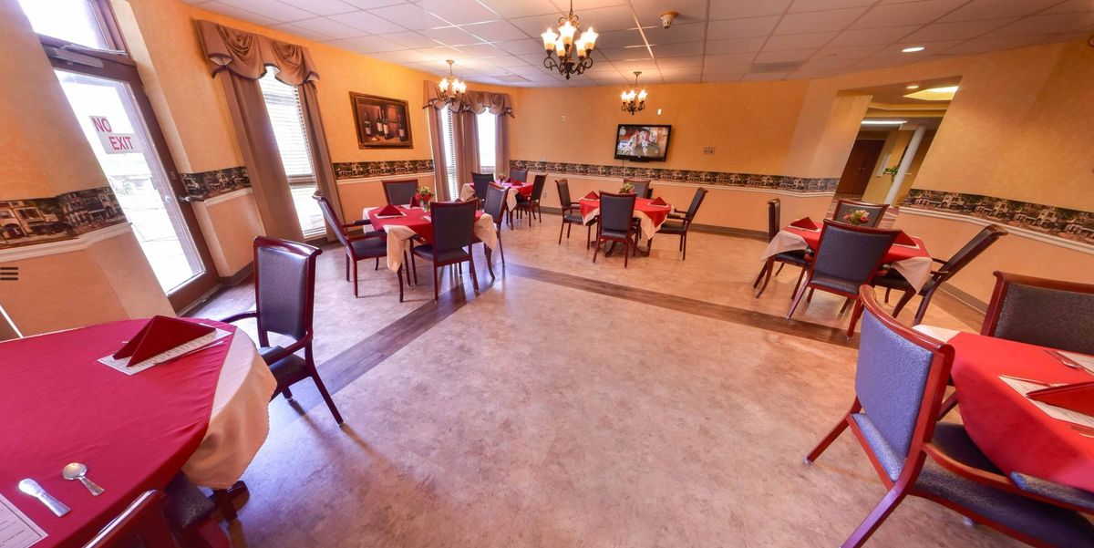 An elegant dining room with several tables and chairs, adorned with chandeliers and tasteful decor.