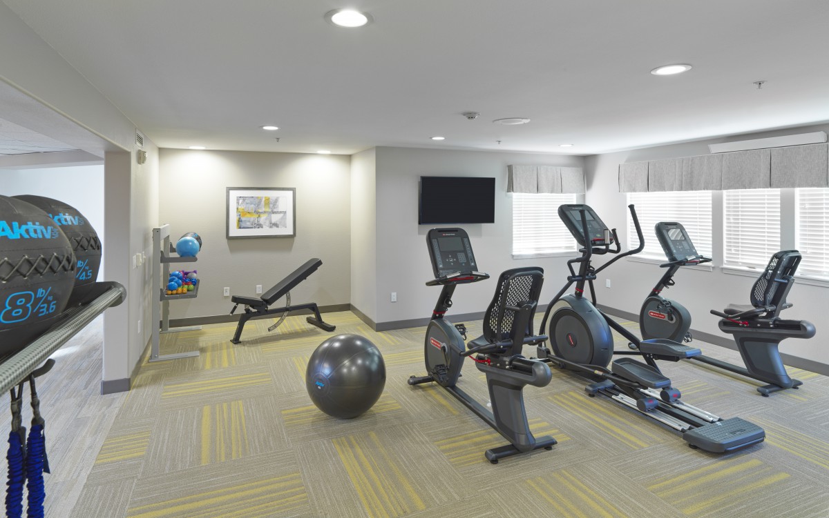 A modern gym with various fitness equipment including exercise bikes and elliptical machines.