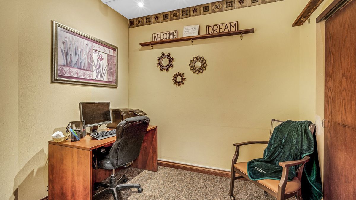 A cozy office space with a computer desk, chair, and decorative wall art.