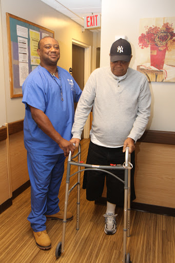 A nurse assists a patient using a walker in a rehabilitation setting.