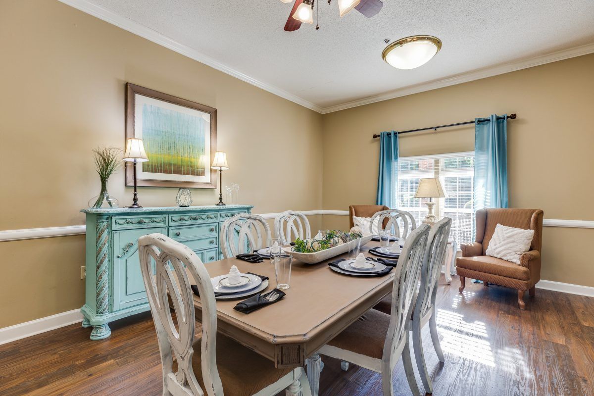 A cozy dining room with a wooden table, matching chairs, and a blue sideboard adorned with decor items.
