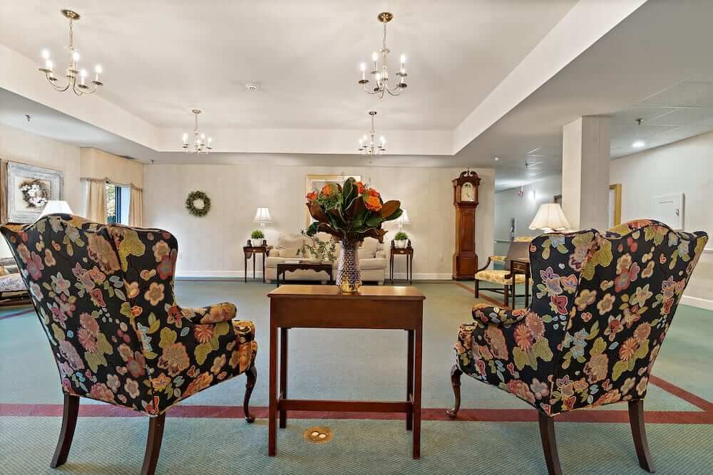 A cozy sitting area with floral chairs and a central table adorned with flowers, set against a backdrop of elegant decor.
