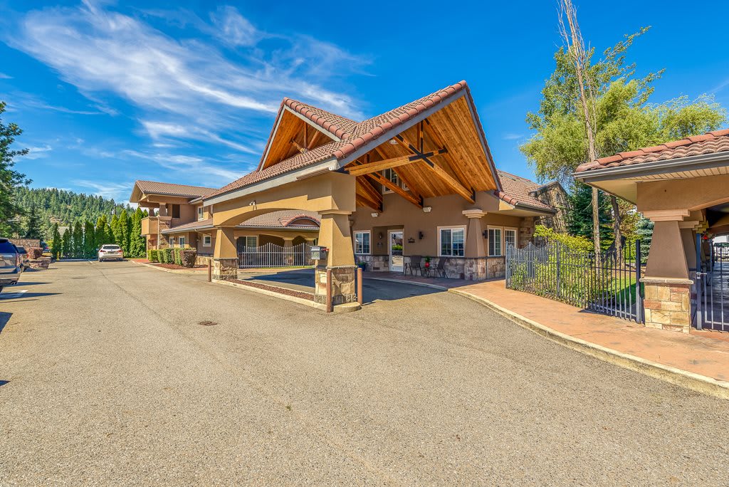 A sunny day view of a large building entrance with a distinctive wooden roof and driveway.