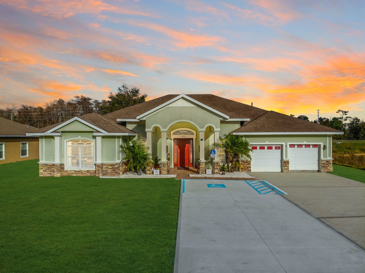 A beautiful residential house with a well-maintained front yard and a driveway at sunset.