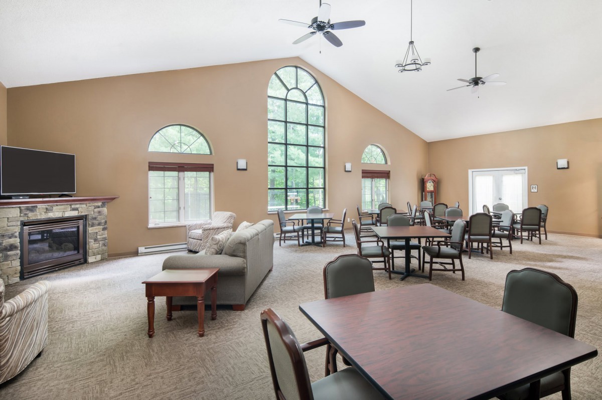 A spacious living area featuring large windows, tables, and comfortable seating.