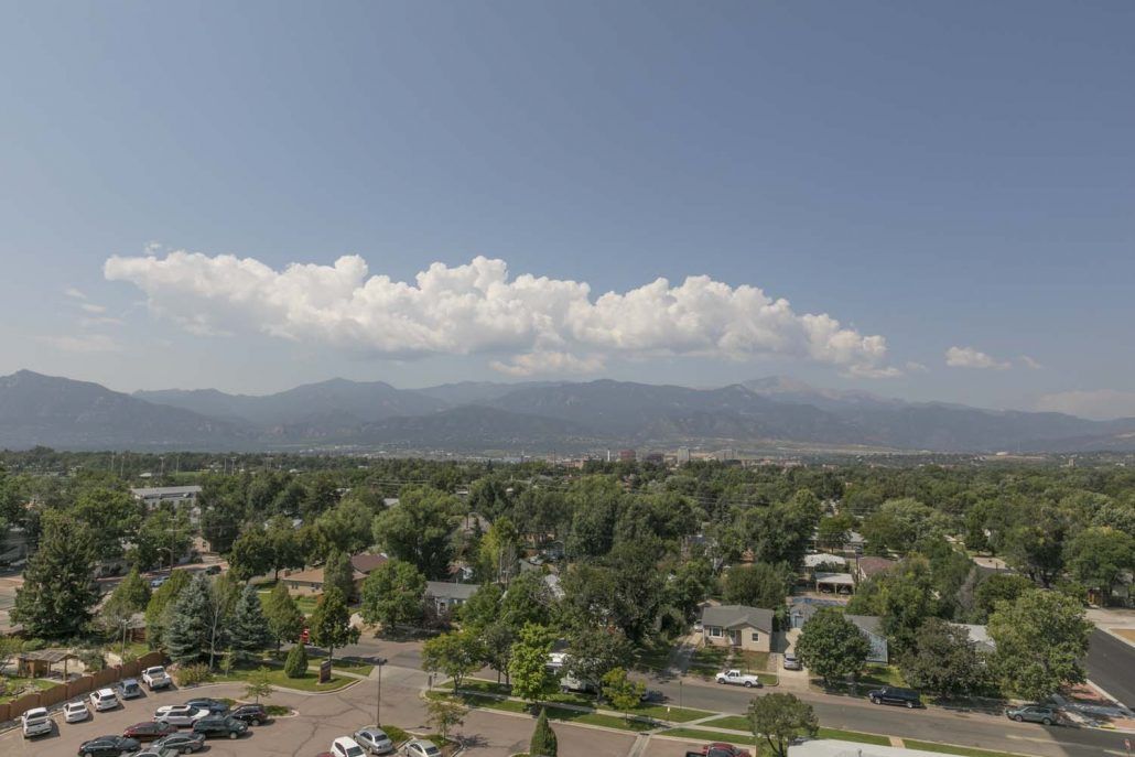 A scenic view of a neighborhood with mountains and clouds in the background.