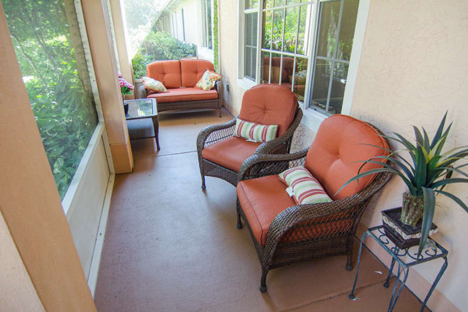 A cozy porch with wicker furniture and vibrant cushions, perfect for relaxing outdoors.