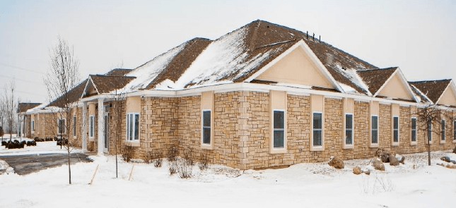 A brick house with a snow-covered roof during winter.