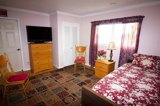 A cozy bedroom featuring a floral bedspread, wooden furniture, and a television.