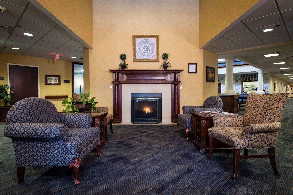 A cozy hotel lobby featuring comfortable seating, a central fireplace, and elegant decor.