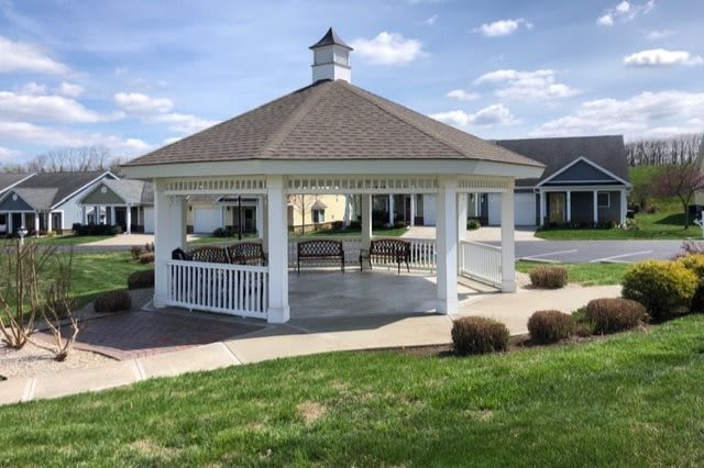 A picturesque white gazebo set in a park with green grass and a blue sky.