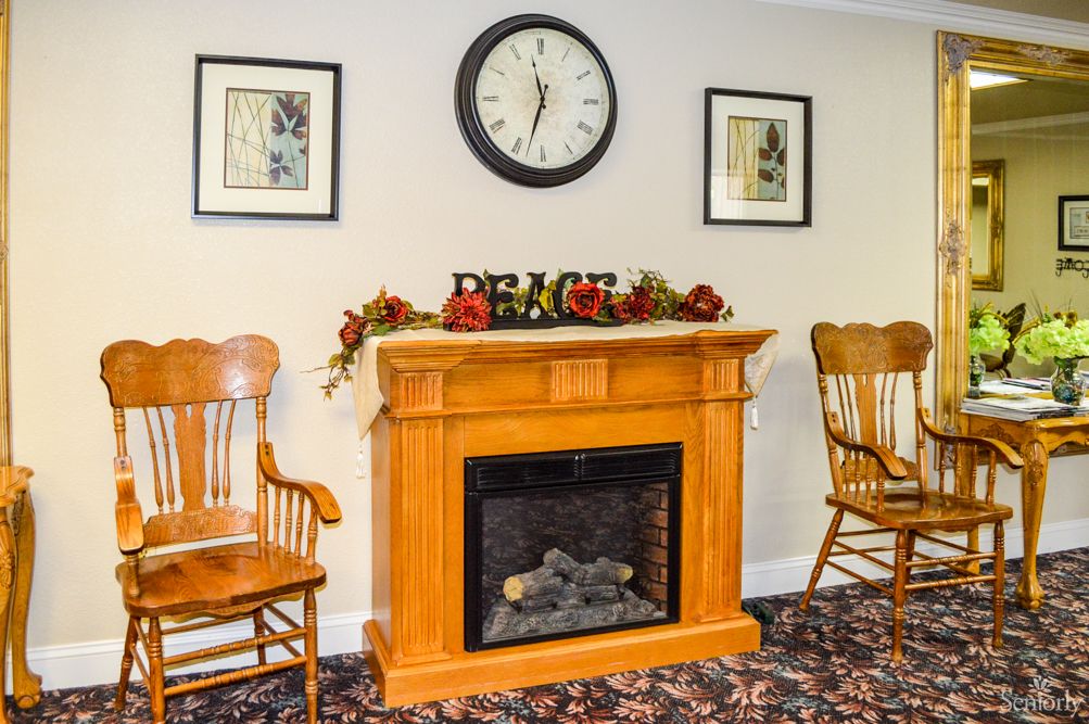Cozy room with a wooden fireplace, clock, and two chairs.