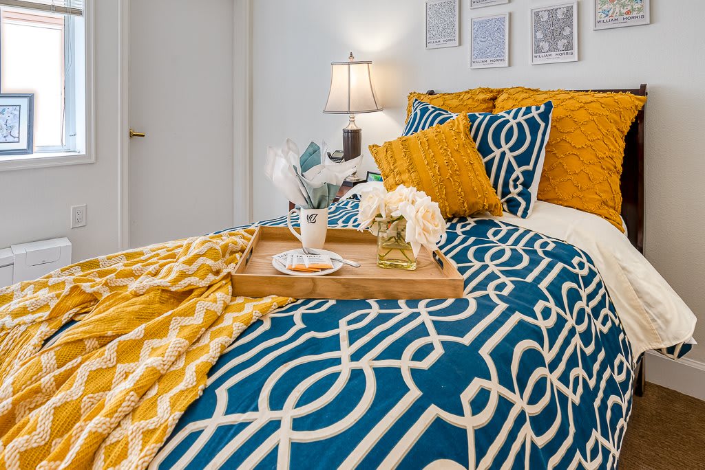 A stylish bedroom with geometric patterned bedding and a decorative tray on the bed.