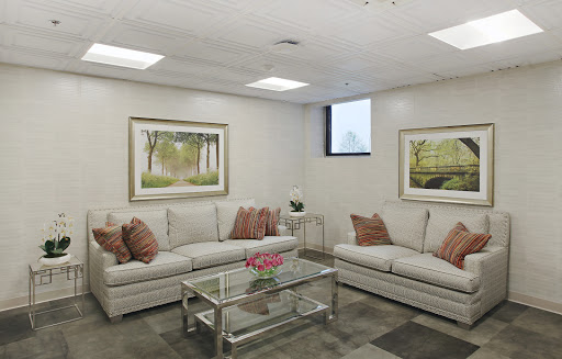 A cozy and elegantly designed living room featuring a comfortable white sofa, decorative pillows, and framed artworks on the walls.