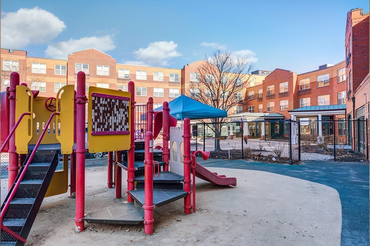 A colorful playground with slides and climbing structures amid an urban backdrop.
