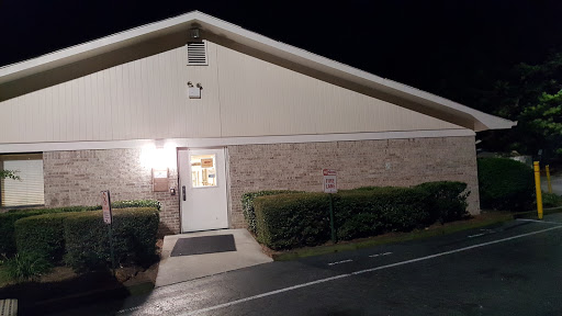A well-lit building entrance at night, showcasing brick and landscaping.