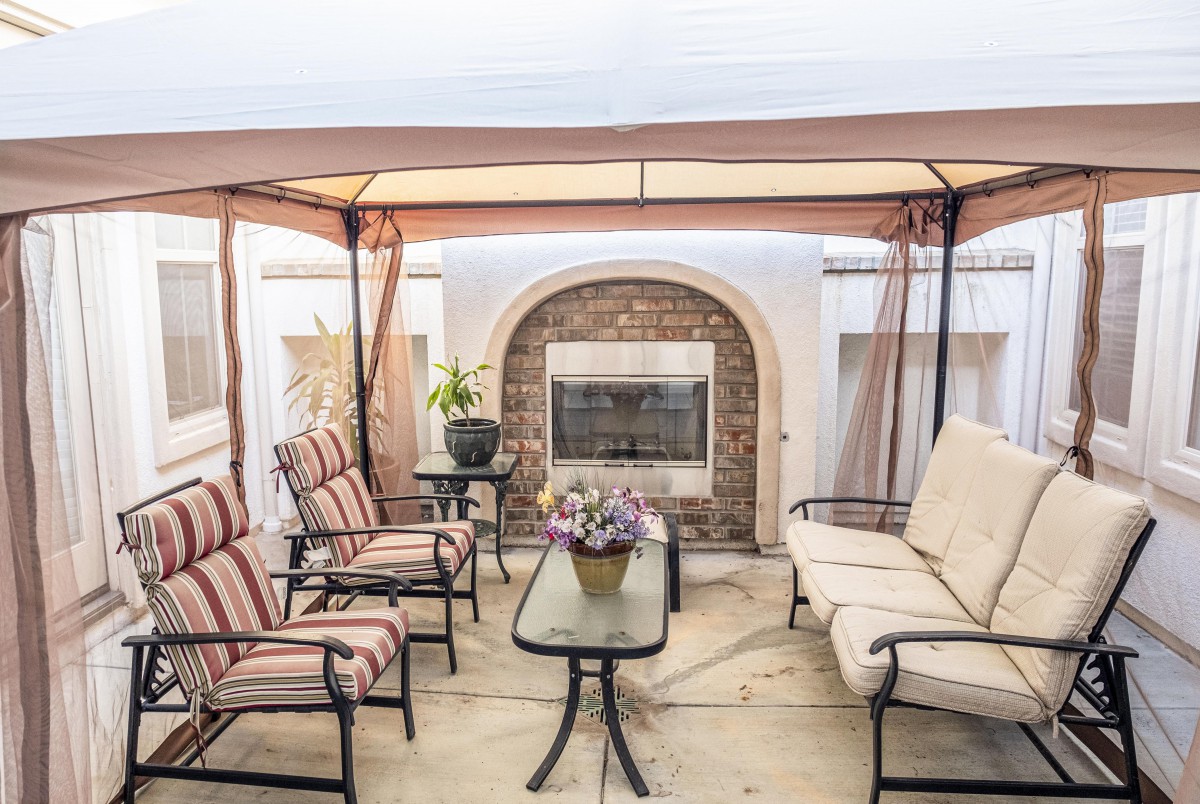 Cozy outdoor gazebo with a fireplace and comfortable seating area.