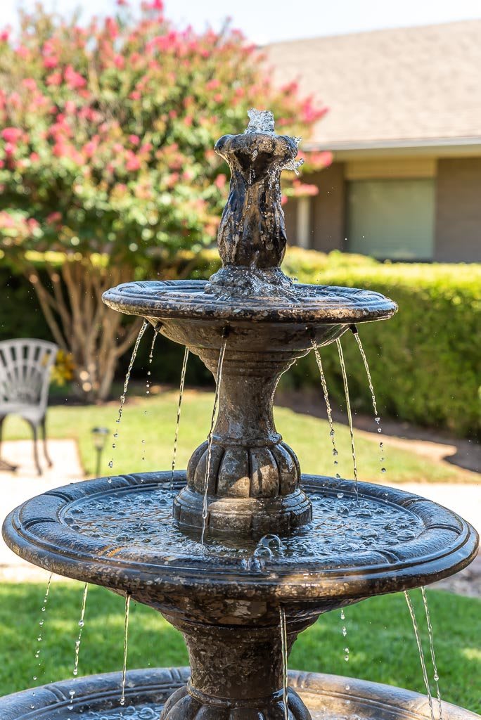 A decorative garden fountain with flowing water surrounded by greenery.