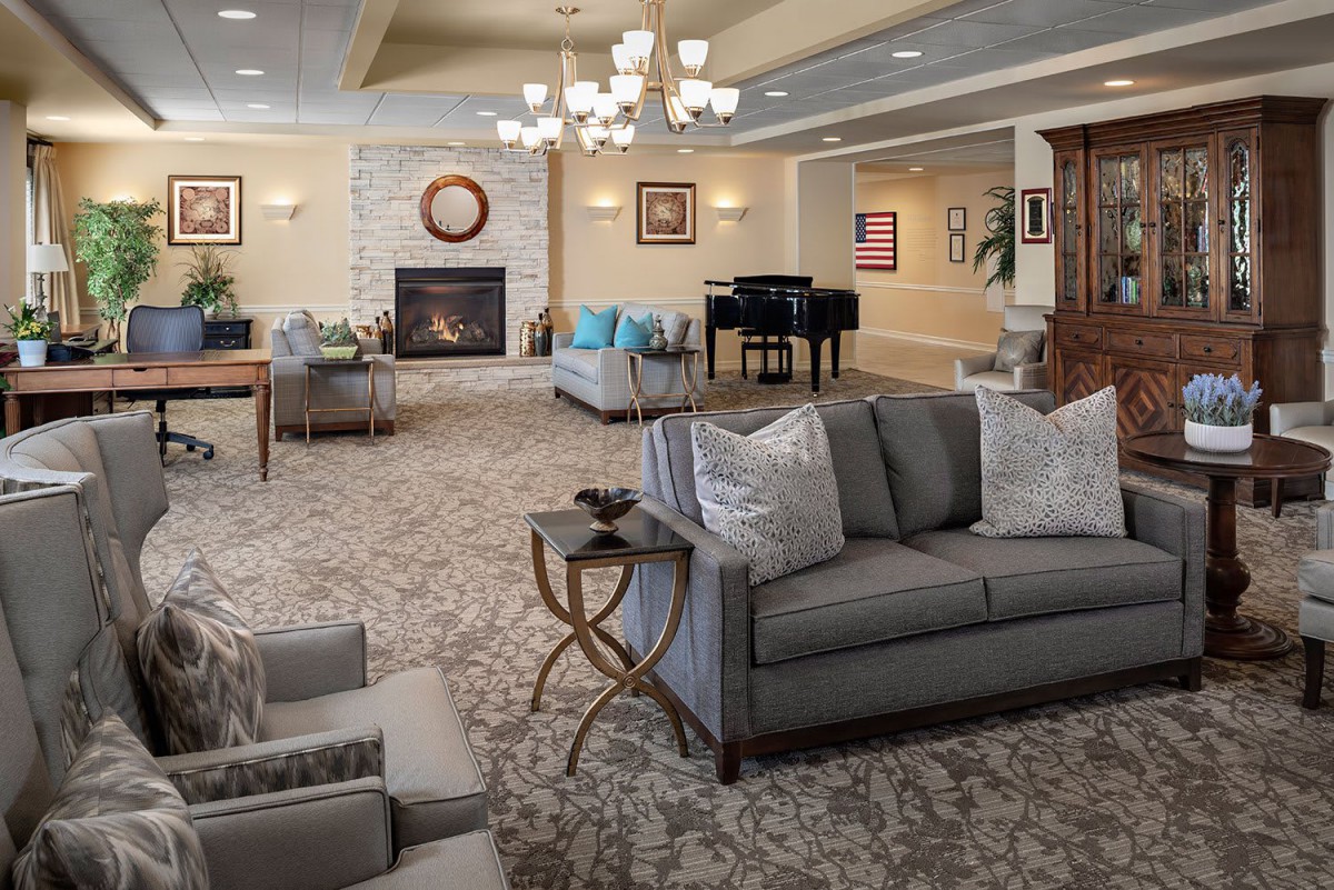 A spacious and elegantly decorated living room featuring comfortable sofas, a fireplace, and a grand piano.