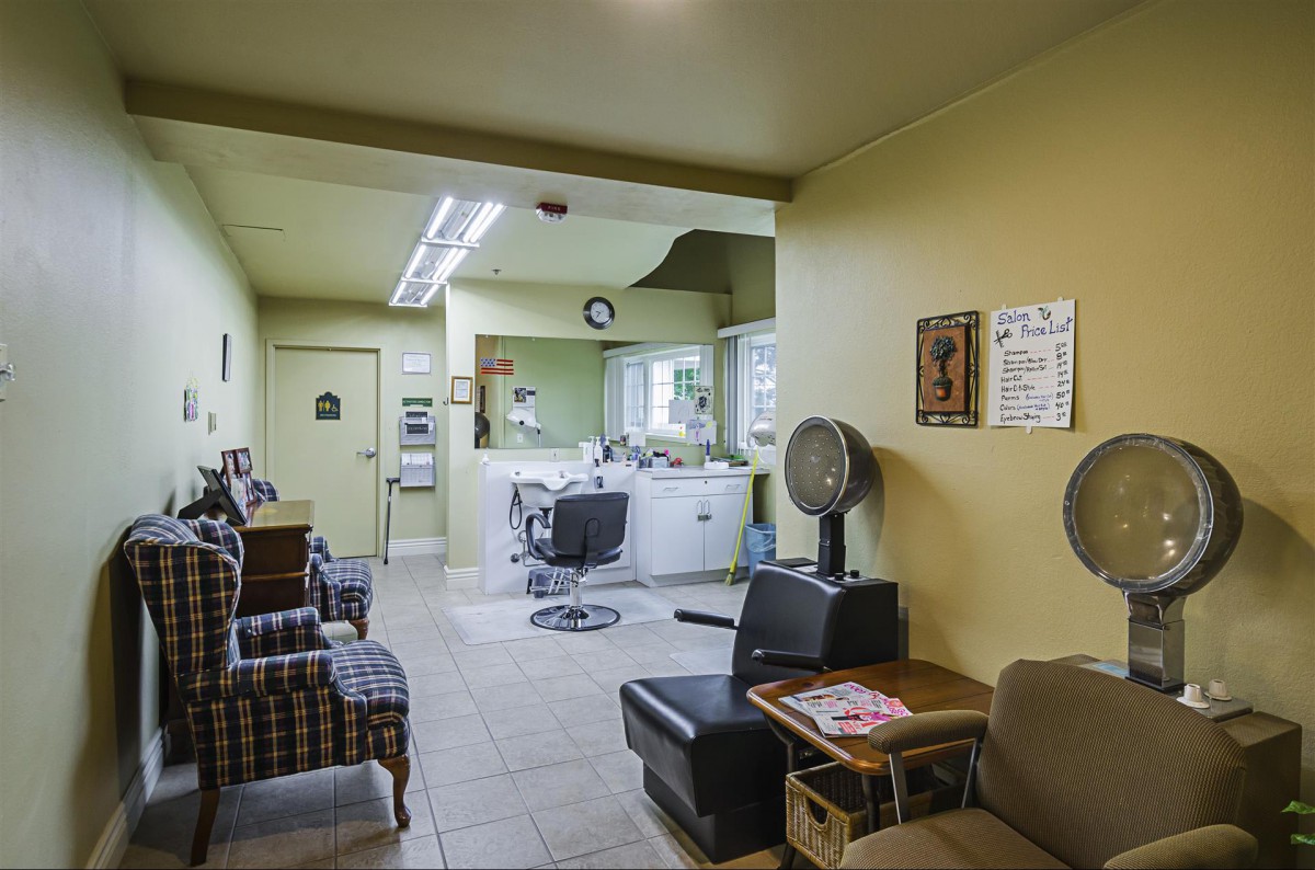 A cozy barbershop interior with a waiting area, hair styling station, and classic salon chairs.